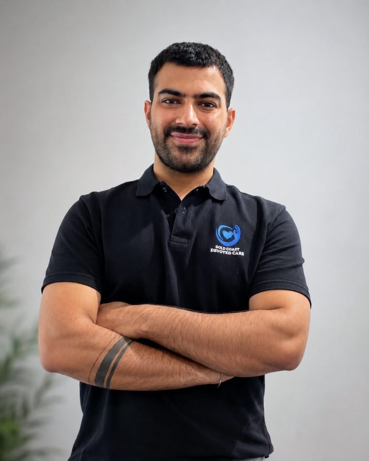 Ritik Lal, Founder and Director of Gold Coast Devoted Care, standing with his arms folded and wearing a Gold Coast Devoted Care polo shirt.